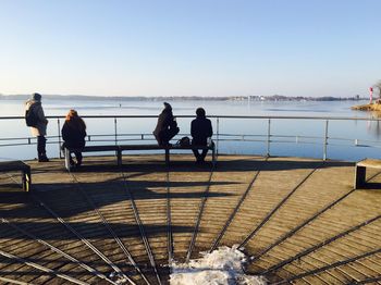 People by sea against clear sky