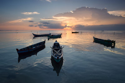 Boat moored in sea against sky during sunset