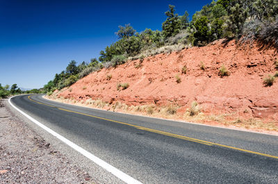 Empty road against clear blue sky