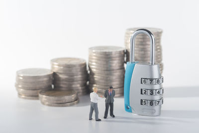 Padlock and figurines with stacked coins over white background