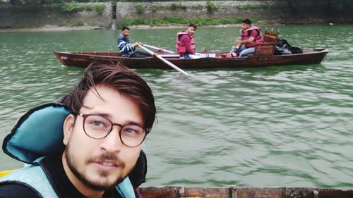 Handsome man wearing eyeglasses with friends on rowboat in river