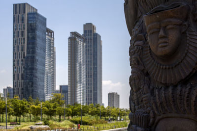 Carved wooden sculpture with modern buildings in background