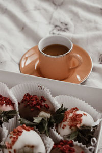 Chocolate covered strawberries with an espresso in an light orange cup 