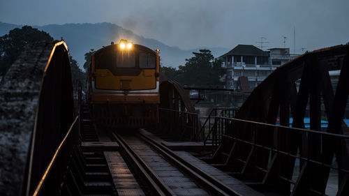 Antique steam train across river kwai bridge in early morning, kanchanaburi, thailand. 