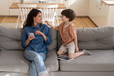 Friends sitting on sofa at home