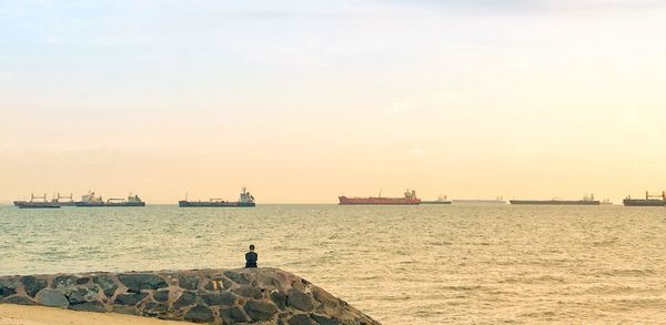 Silhouette man on sea against sky during sunset