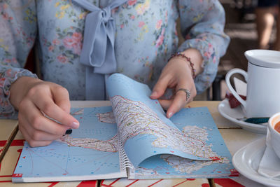 Midsection of woman analyzing map while sitting at table