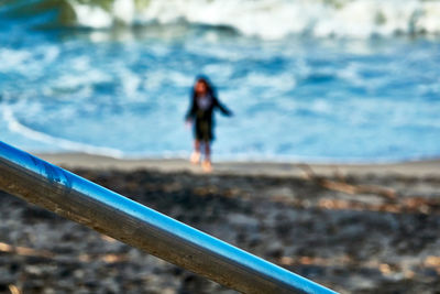 Woman with umbrella walking on sea shore