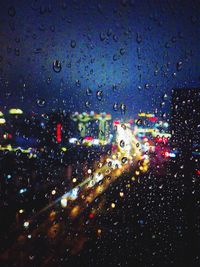 Illuminated cars seen through wet windshield at night