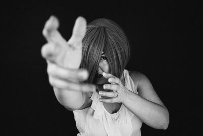 Portrait of woman gesturing against black background