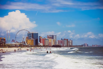 View of amusement park by sea against sky