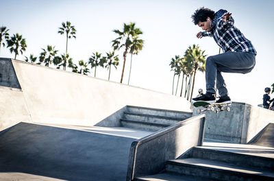 Side view of man skateboarding on street against sky