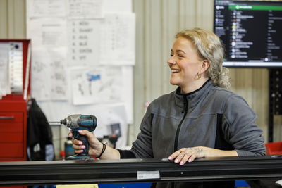 Woman using drilling machine in factory