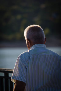 Rear view of man standing by lake