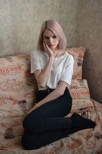 Young woman sitting on bed at home