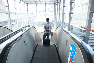 Rear view of man standing on escalator