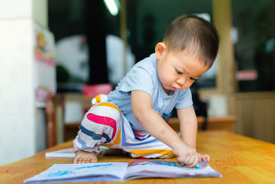 Boy drawing on book at table