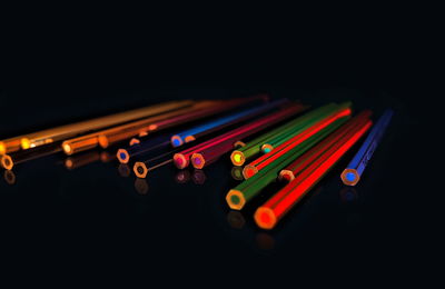 Close-up of pencil illuminated lights over black background