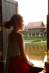 Woman looking away while standing against sky