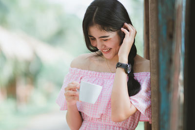 Close-up of smiling young woman holding coffee cup