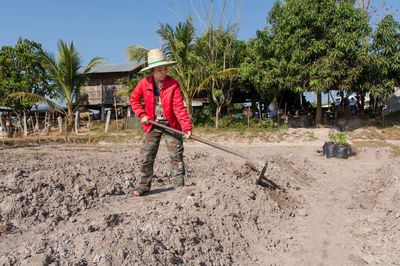 Full length of female farmer wearing hat while working in farm