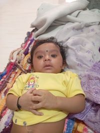 Portrait of cute baby lying on bed at home