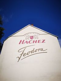 Low angle view of information sign against clear blue sky