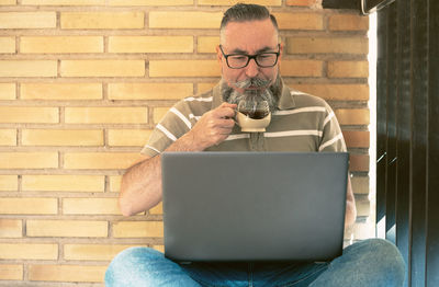 Young man using laptop while sitting on sofa at home