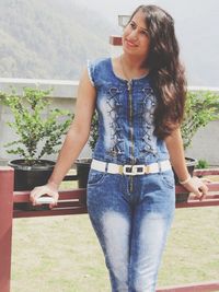 Smiling young woman looking away while standing by railing