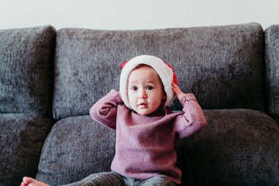 Cute smiling baby girl sitting on sofa at home