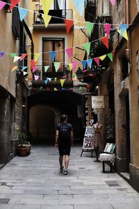 Rear view of people walking on footpath amidst buildings