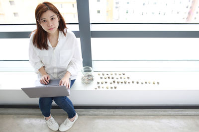 Portrait of woman using laptop while sitting on seat in office