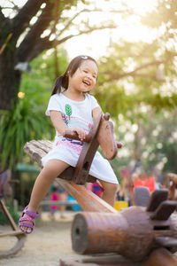 Happy girl playing on seesaw in playground