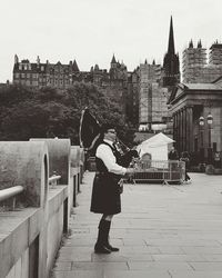 Rear view of woman walking in city against sky