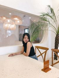 Portrait of young woman sitting against wall