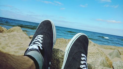 Low section of man on beach against sky