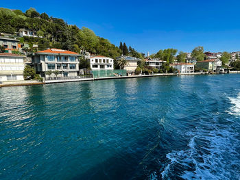 Buildings by sea against blue sky