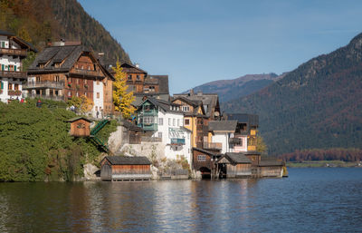 Houses by river and buildings against sky