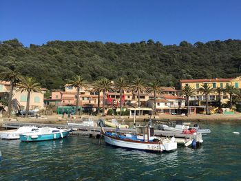 Boats moored in water against clear blue sky