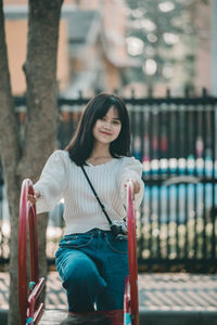 Portrait of young woman holding camera