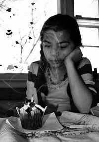 Girl with cupcake at table during birthday