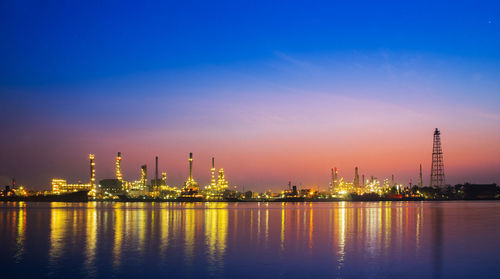 Panoramic view of illuminated factory against sky at night