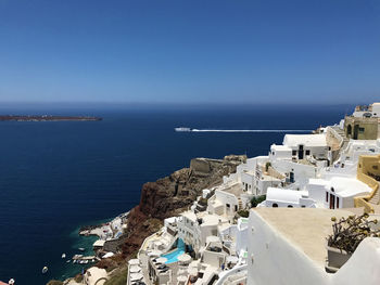 High angle view of town by sea against blue sky