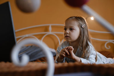 Child watching cartoons on laptop. serious kid with technology at home on bed spending time on-line