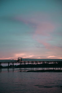 Silhouette pier over sea against sky during sunset