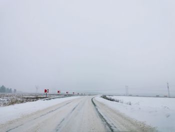 Road amidst snow covered landscape against sky