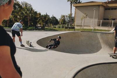 Man skateboarding on sports ramp amidst friends at park