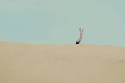 Woman with legs raised on sand dune