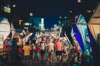 Group of people shopping in city market on street at night