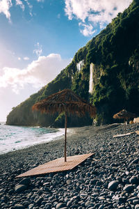 Thatched roof at beach against sky